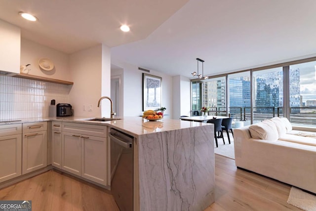 kitchen with dishwasher, light stone counters, pendant lighting, decorative backsplash, and light wood-type flooring