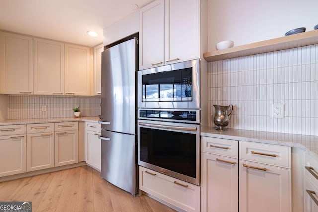 kitchen featuring decorative backsplash, white cabinetry, stainless steel appliances, and light hardwood / wood-style floors