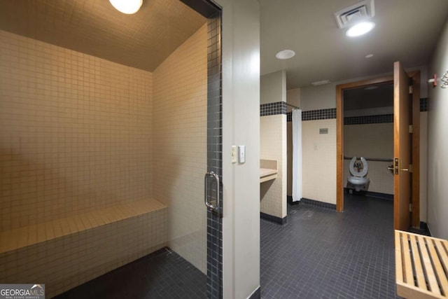 bathroom with tile patterned floors, walk in shower, and tile walls