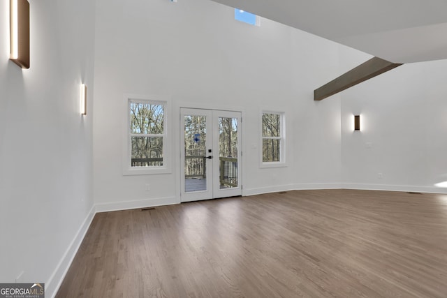 unfurnished living room with french doors, vaulted ceiling, and hardwood / wood-style flooring