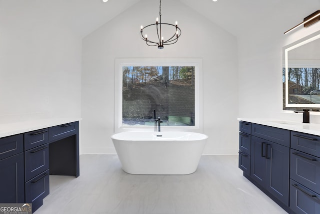 bathroom featuring vanity, vaulted ceiling, a notable chandelier, and a bathtub