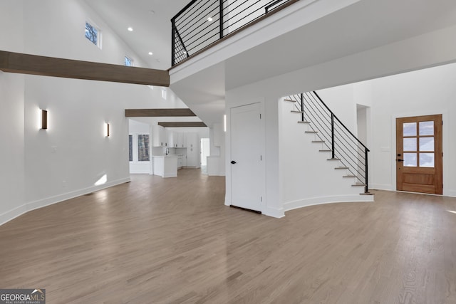 unfurnished living room with a towering ceiling and light wood-type flooring