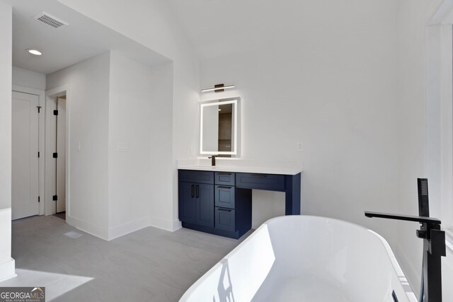 bathroom featuring a bathing tub, lofted ceiling, and vanity