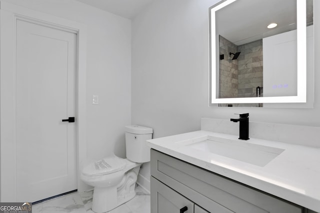 bathroom with vanity, toilet, and tiled shower