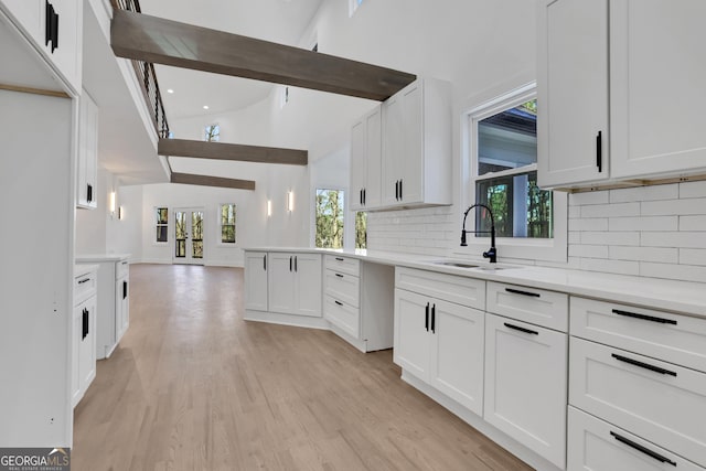 kitchen with tasteful backsplash, sink, vaulted ceiling, and white cabinets