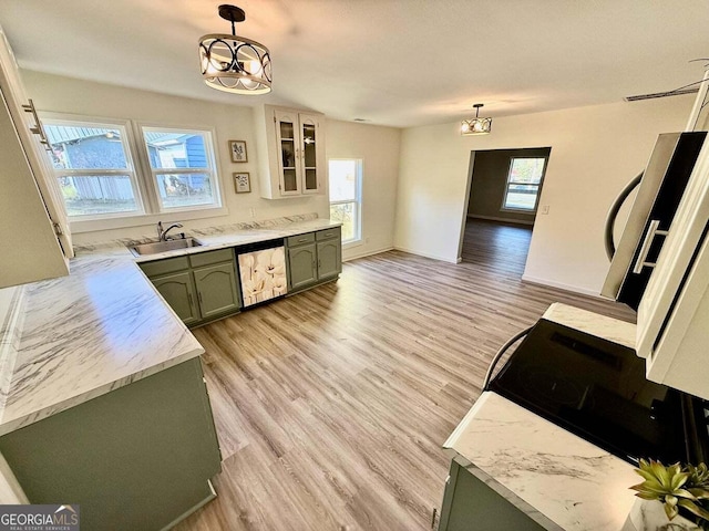 kitchen featuring green cabinets, sink, decorative light fixtures, and a notable chandelier