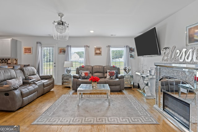 living room with light wood-type flooring and an inviting chandelier