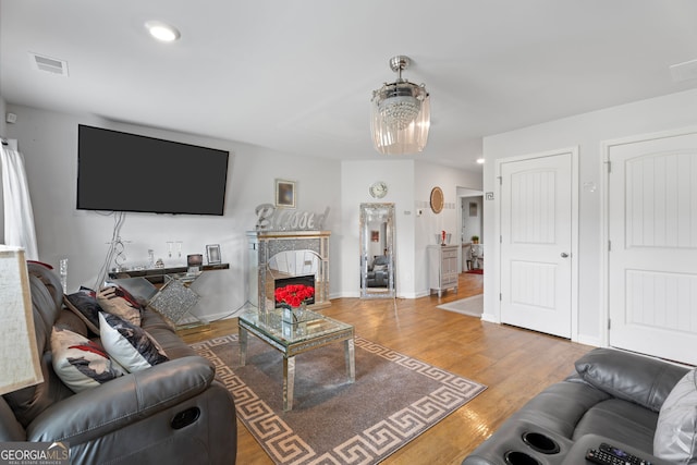 living room featuring hardwood / wood-style floors, a notable chandelier, and a premium fireplace