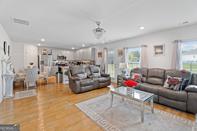 living room featuring a chandelier, light wood-type flooring, and a wealth of natural light