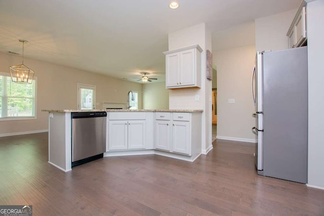 kitchen with appliances with stainless steel finishes, ceiling fan with notable chandelier, white cabinetry, and light stone counters