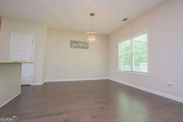 empty room with a chandelier and dark wood-type flooring