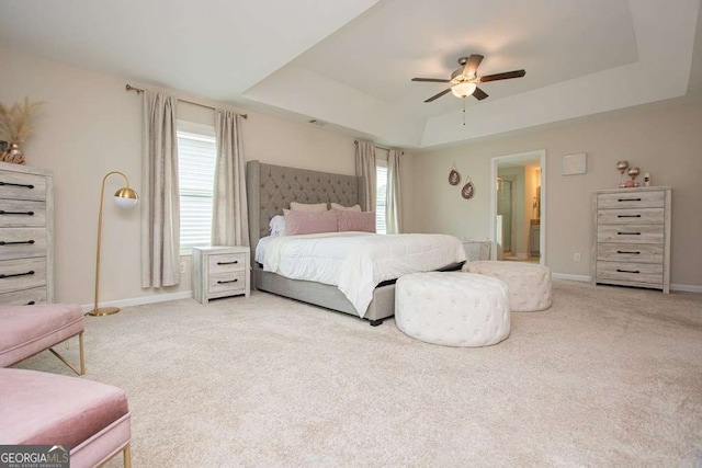 bedroom with carpet, ceiling fan, a raised ceiling, and multiple windows