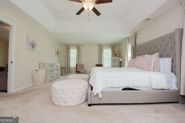 bedroom with light carpet, a raised ceiling, and ceiling fan