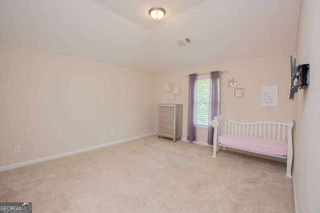 unfurnished bedroom featuring light carpet and a nursery area