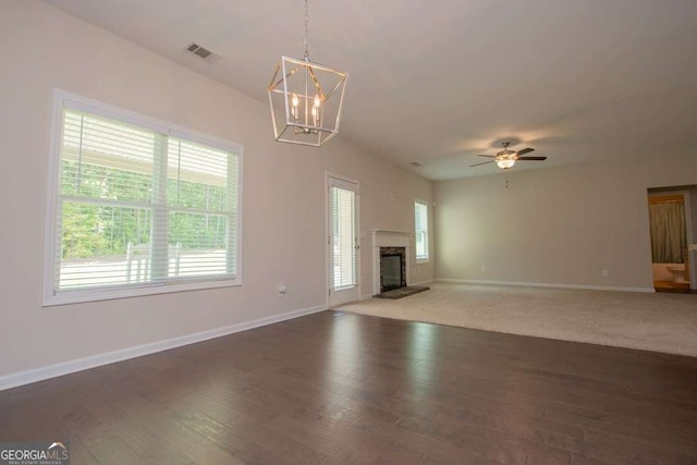 unfurnished living room featuring ceiling fan with notable chandelier and dark hardwood / wood-style flooring