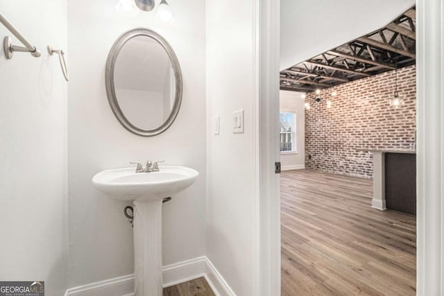 bathroom featuring hardwood / wood-style flooring and brick wall