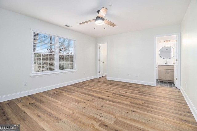 unfurnished bedroom featuring ceiling fan, light wood-type flooring, sink, and connected bathroom