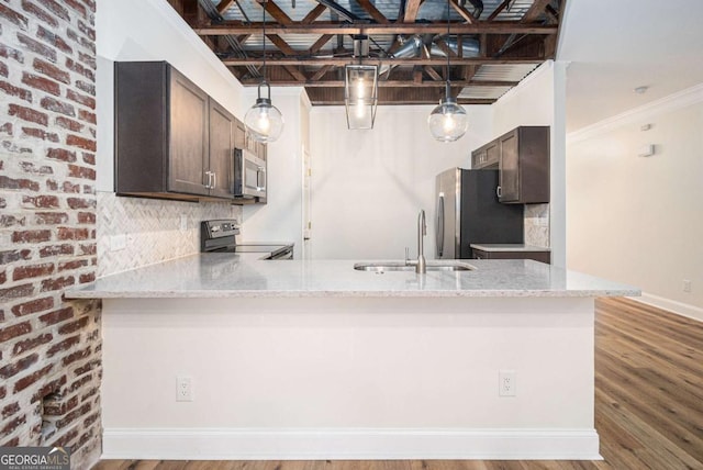 kitchen featuring kitchen peninsula, appliances with stainless steel finishes, light stone countertops, dark brown cabinets, and sink