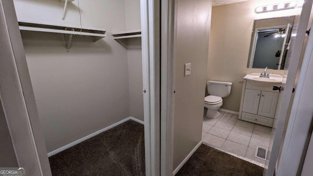 bathroom with toilet, vanity, tile patterned floors, and ceiling fan