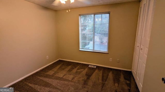 carpeted empty room with ceiling fan and a textured ceiling