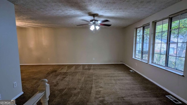 empty room featuring a textured ceiling, dark carpet, and ceiling fan