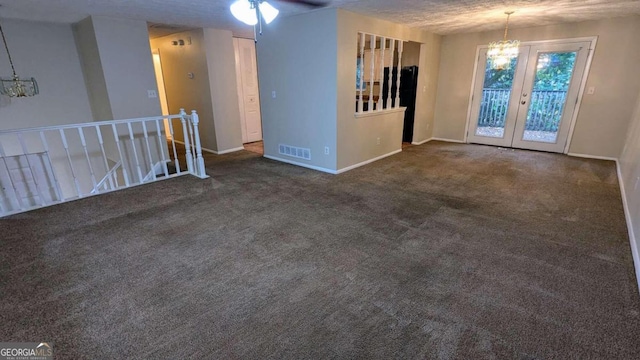 unfurnished room with dark colored carpet, ceiling fan with notable chandelier, and a textured ceiling