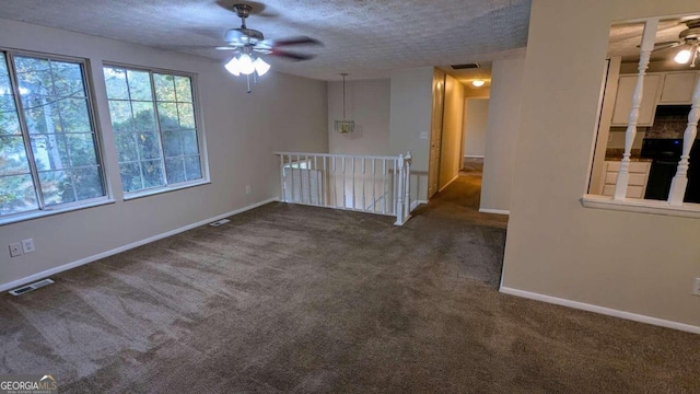 carpeted spare room featuring ceiling fan and a textured ceiling