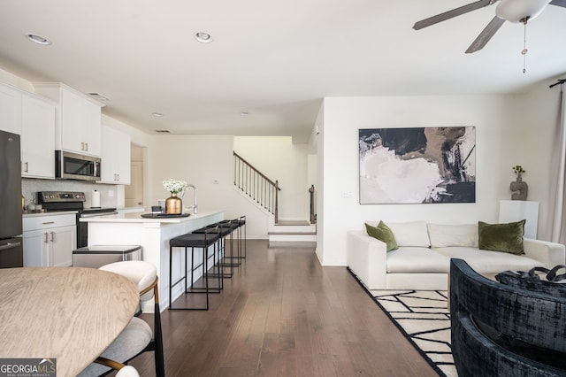 living room featuring dark hardwood / wood-style flooring and ceiling fan