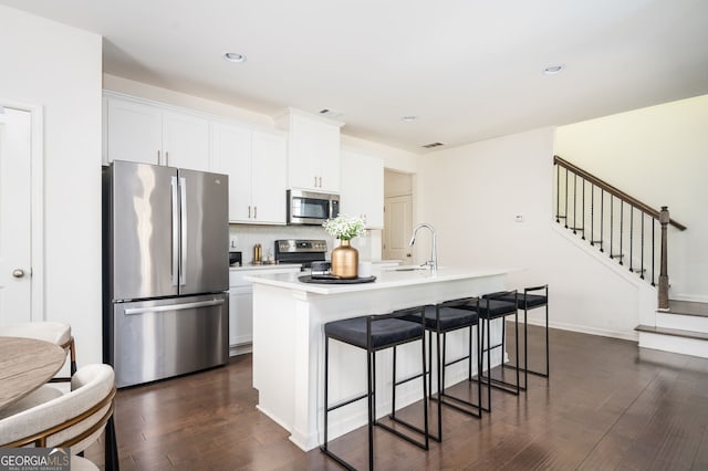 kitchen with white cabinetry, a kitchen island with sink, appliances with stainless steel finishes, and dark wood-type flooring