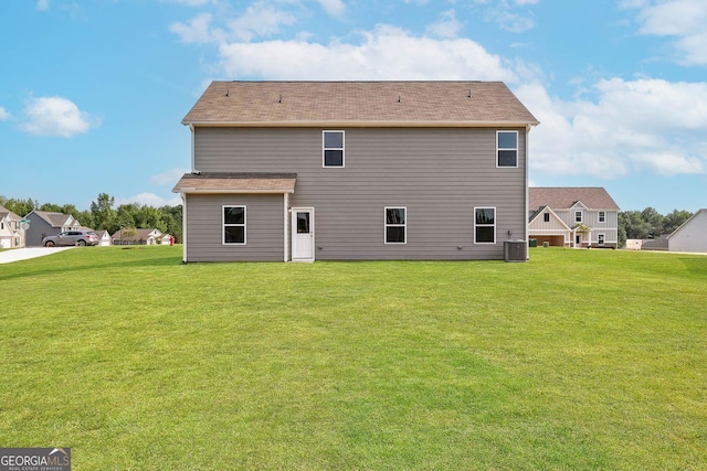 rear view of house featuring a yard and central air condition unit