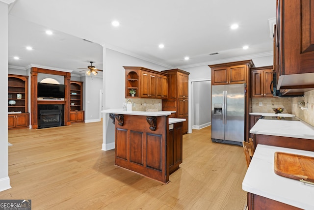 kitchen with ceiling fan, a center island, stainless steel refrigerator with ice dispenser, a kitchen bar, and decorative backsplash