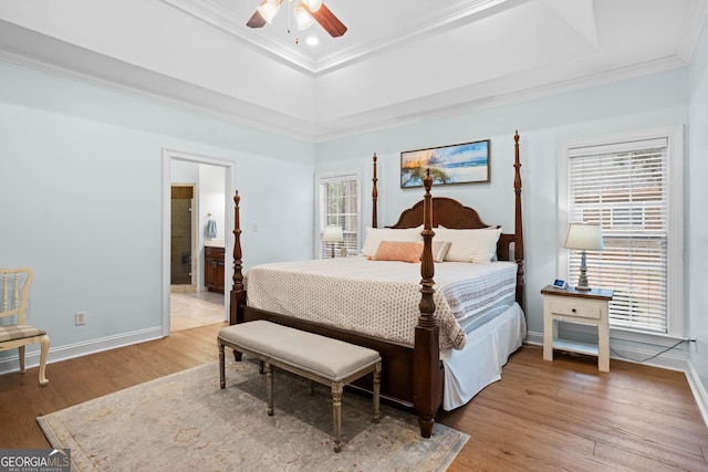 bedroom with a tray ceiling, ceiling fan, ensuite bathroom, and ornamental molding