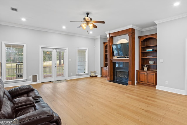 living room with ceiling fan, ornamental molding, french doors, and light hardwood / wood-style flooring