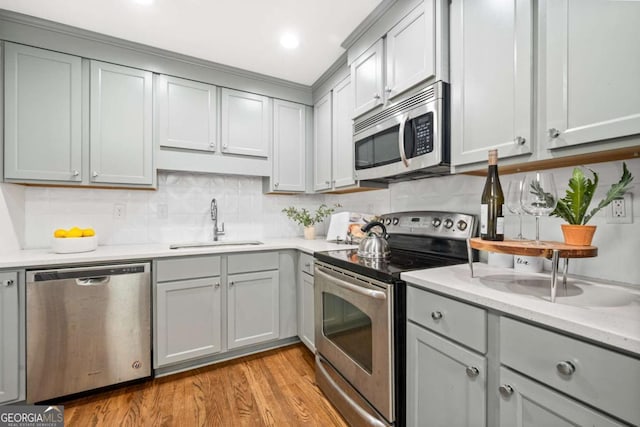 kitchen featuring light stone countertops, sink, stainless steel appliances, light hardwood / wood-style floors, and decorative backsplash