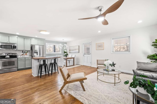 living room featuring ceiling fan with notable chandelier and light hardwood / wood-style floors