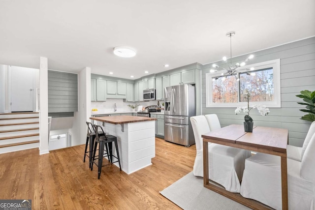 kitchen with light hardwood / wood-style flooring, a kitchen island, hanging light fixtures, and appliances with stainless steel finishes