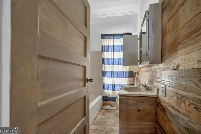 bathroom with shower / bath combo, vanity, decorative backsplash, and wooden walls