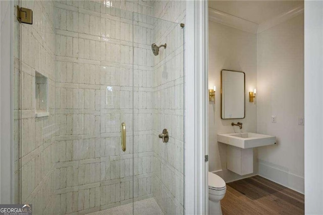 bathroom featuring hardwood / wood-style floors, sink, crown molding, toilet, and a shower with shower door