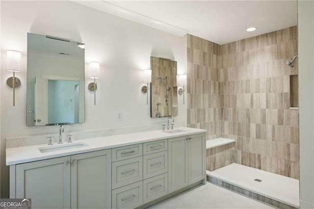 bathroom with tile patterned flooring, a tile shower, and vanity