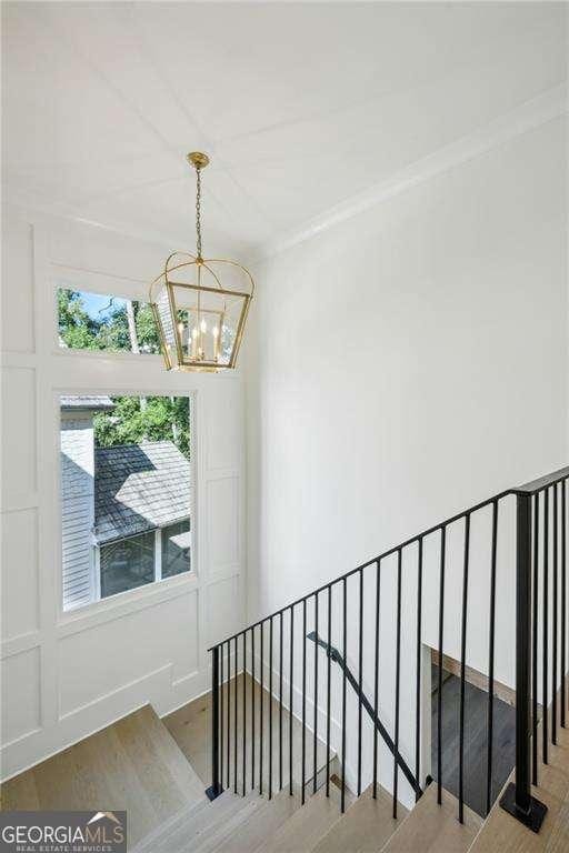 staircase with crown molding, a chandelier, and hardwood / wood-style flooring