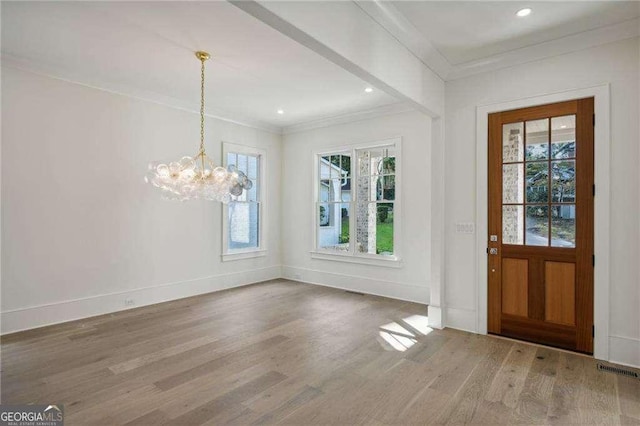 foyer with hardwood / wood-style floors, an inviting chandelier, and ornamental molding