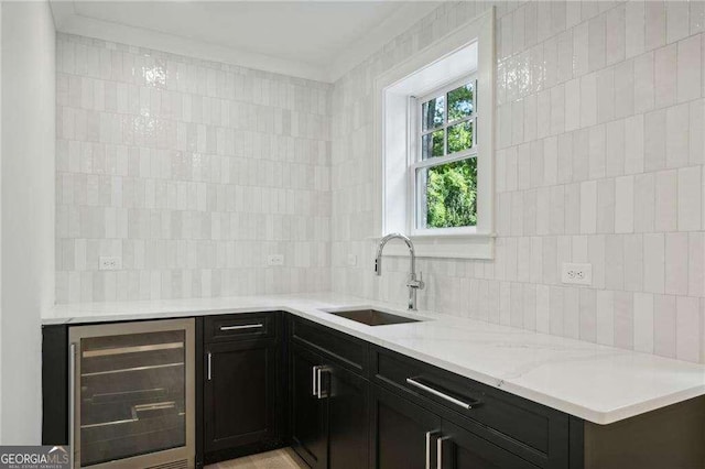 kitchen with sink, beverage cooler, tasteful backsplash, light stone counters, and tile walls