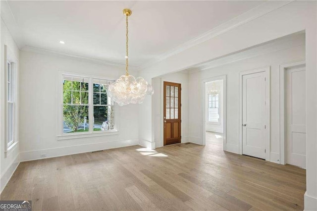 unfurnished dining area with hardwood / wood-style floors, ornamental molding, and an inviting chandelier