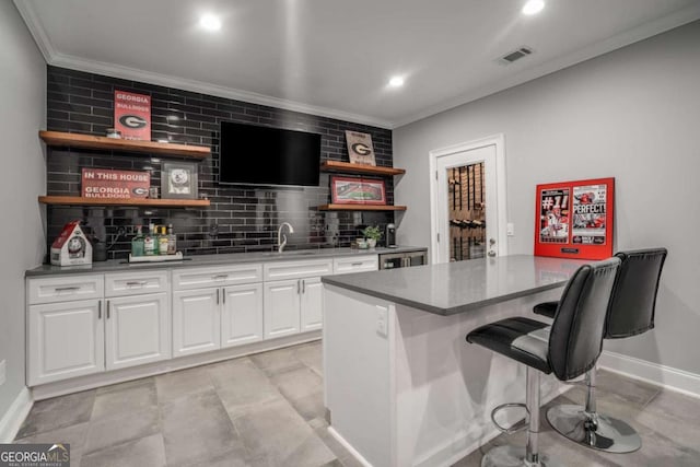 bar featuring white cabinetry, sink, and crown molding