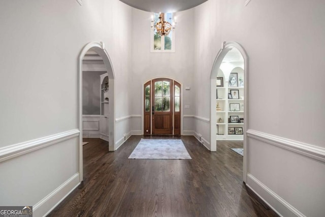 entryway with a notable chandelier, dark hardwood / wood-style flooring, and a high ceiling