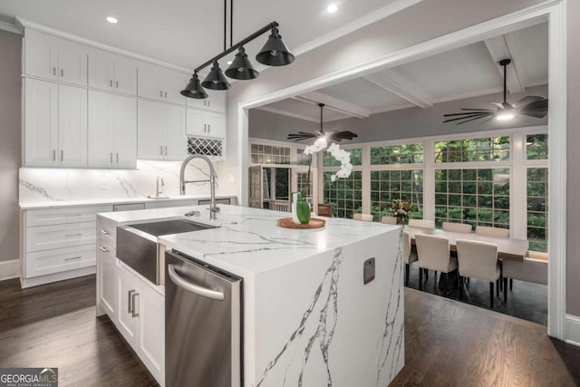 kitchen with beam ceiling, white cabinetry, dishwasher, ceiling fan, and a kitchen island with sink