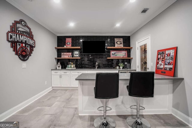 bar featuring white cabinets, decorative backsplash, sink, and crown molding