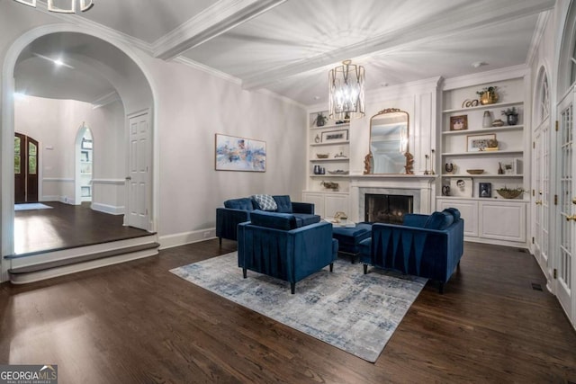 living room featuring dark wood-type flooring, crown molding, built in features, and a chandelier