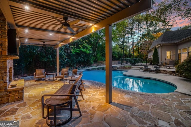 pool at dusk with ceiling fan and a patio