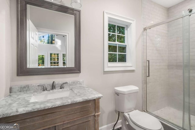 bathroom featuring vanity, toilet, and a shower with shower door